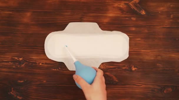 Menstruační pad, na dřevěné pozadí, nalil modrá tekutina. — Stock video