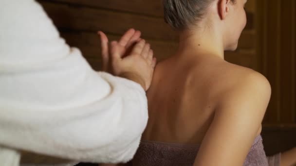 Un hombre hace un masaje de espalda y cuello hermosa mujer en la sauna, baño . — Vídeo de stock