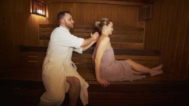 Ein Mann macht eine Rücken- und Nackenmassage schöne Frau in der Sauna, Bad. — Stockvideo