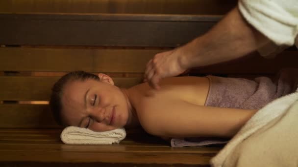 Um homem faz uma massagem nas costas e pescoço bela mulher na sauna, banho . — Vídeo de Stock