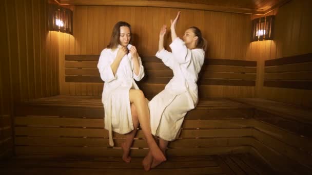 Zwei glückliche Frauen im Gespräch miteinander in einer Sauna — Stockvideo