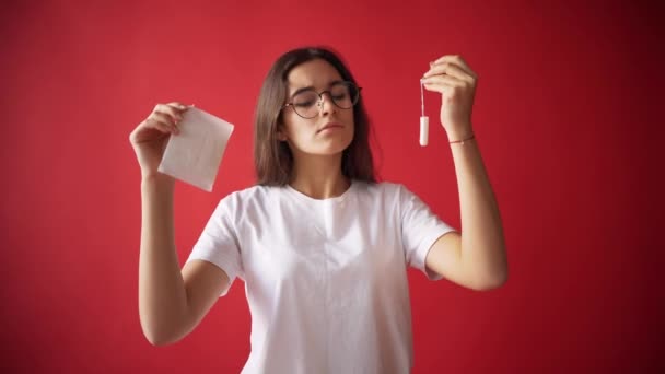 Koncepcja miesiączki, owulacji u dziewcząt. Dziewczyna na czerwonym tle gospodarstwa tampon, uszczelka. — Wideo stockowe