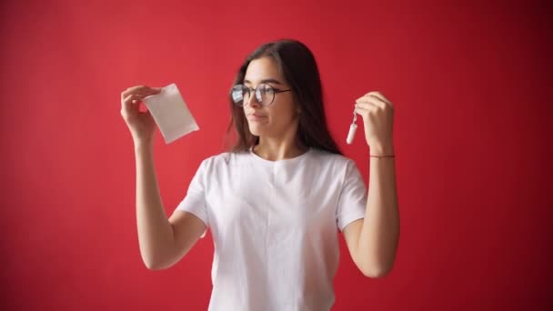 El concepto de menstruación, ovulación en las niñas. Chica sobre un fondo rojo sosteniendo un tampón, junta . — Vídeo de stock