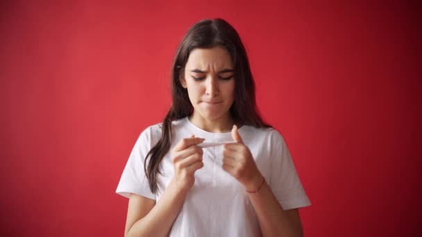 Il concetto di mestruazioni, ovulazione nelle ragazze. Ragazza su uno sfondo rosso che tiene un tampone, guarnizione . — Video Stock
