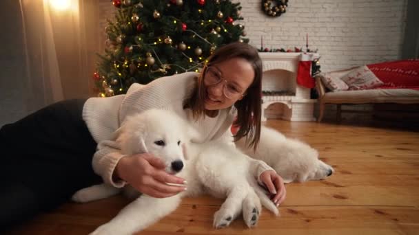 Flicka som leker med glad valp på bakgrunden av julgran och öppen spis — Stockvideo