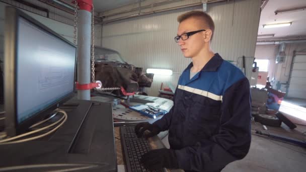 Portrait of a young beautiful car mechanic in the car workshop, on the background of a broken car. Concept: machine repair, fault diagnosis, specialist repair, maintenance. — Stock Video