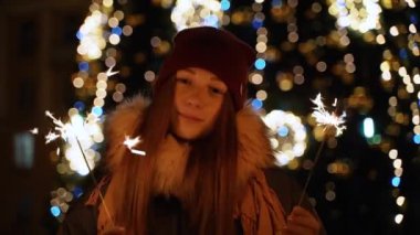 Bir kız bir Bengal ışık açık Noel ağacına tutar.