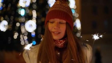 Bir kız bir Bengal ışık açık Noel ağacına tutar.