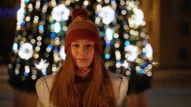 Bir kız bir Bengal ışık açık Noel ağacına tutar.