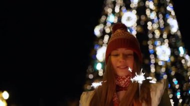 Bir kız bir Bengal ışık açık Noel ağacına tutar.