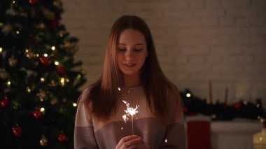 Bir kız bir Bengal ışık açık Noel ağacına tutar.