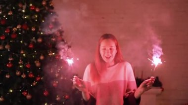 Bir kız bir Bengal ışık açık Noel ağacına tutar.