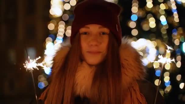Uma menina segura uma frente de luz de Bengala para a árvore de Natal — Vídeo de Stock