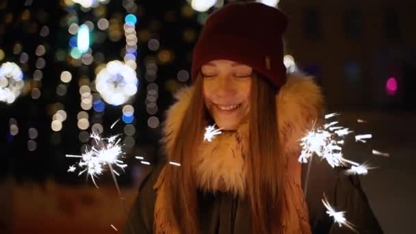 Una ragazza tiene una luce del Bengala davanti all'albero di Natale — Video Stock
