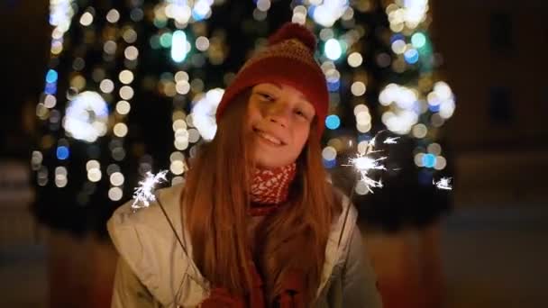 Une fille tient une lumière du Bengale devant l'arbre de Noël — Video