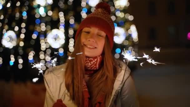 Une fille tient une lumière du Bengale devant l'arbre de Noël — Video