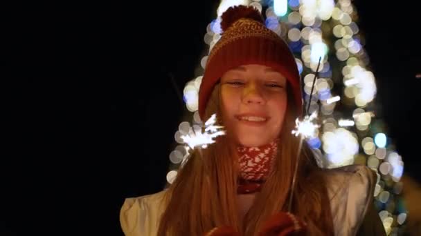 Una ragazza tiene una luce del Bengala davanti all'albero di Natale — Video Stock