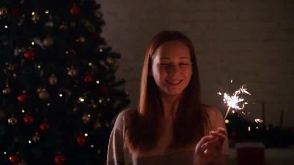 A girl holds a Bengal light front to the christmas tree — Stock Video