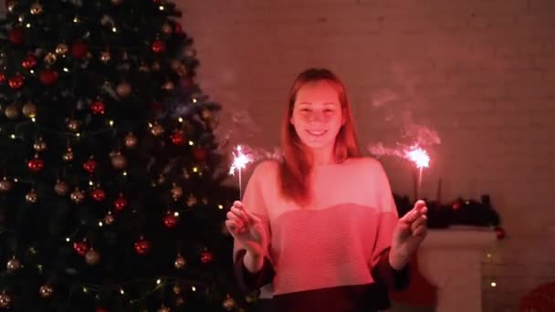 Ένα Κορίτσι Κατέχει Ένα Βεγγάλη Φως Μπροστά Στο Χριστουγεννιάτικο Δέντρο — Αρχείο Βίντεο