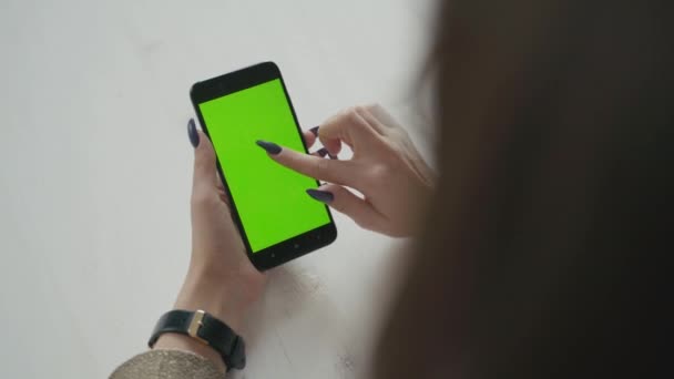 Mooi meisje met een smartphone in de handen van een groen scherm groen scherm. — Stockvideo