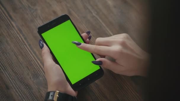 Hermosa chica sosteniendo un teléfono inteligente en las manos de una pantalla verde pantalla verde. — Vídeo de stock