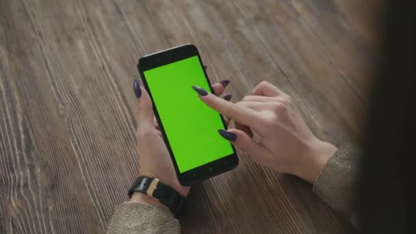 Schöne Mädchen hält ein Smartphone in den Händen eines grünen Bildschirms. — Stockvideo