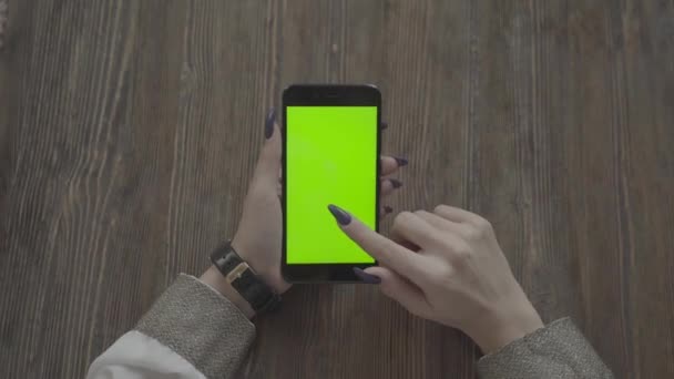 Schöne Mädchen hält ein Smartphone in den Händen eines grünen Bildschirms. — Stockvideo