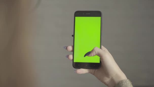 Menina bonita segurando um smartphone nas mãos de uma tela verde tela verde. — Vídeo de Stock