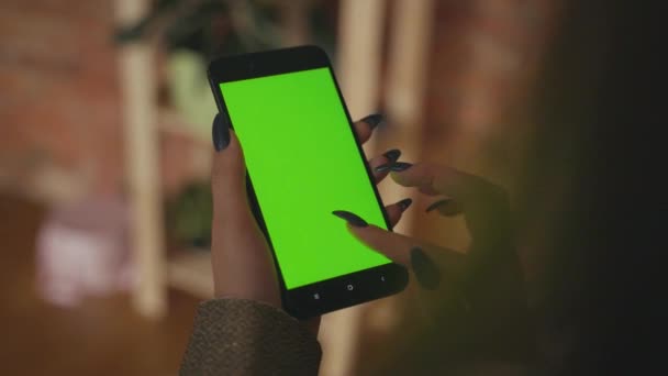 Красивая девушка держит смартфон в руках зеленого экрана. — стоковое видео