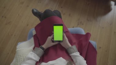 Yeşil ekran. Cep telefonuyla chroma anahtar ile uzun siyah saçlı genç beyaz kadın omuz çekim üzerinde