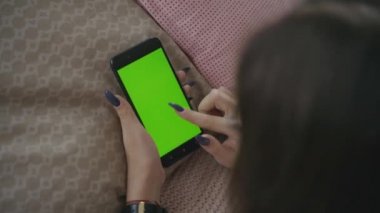 Yeşil ekran. Cep telefonuyla chroma anahtar ile uzun siyah saçlı genç beyaz kadın omuz çekim üzerinde