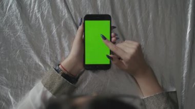 Yeşil ekran. Cep telefonuyla chroma anahtar ile uzun siyah saçlı genç beyaz kadın omuz çekim üzerinde