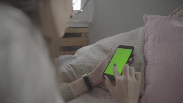 Pantalla verde. Sobre el hombro de la joven mujer caucásica con el pelo largo y negro usando el teléfono móvil con croma key — Vídeos de Stock