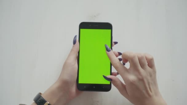 Green Screen. über die Schulter einer jungen kaukasischen Frau mit langen schwarzen Haaren, die ein Mobiltelefon mit Chroma-Schlüssel benutzt — Stockvideo