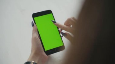 Yeşil ekran. Cep telefonuyla chroma anahtar ile uzun siyah saçlı genç beyaz kadın omuz çekim üzerinde