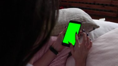 Yeşil ekran yeşil ekranda elinde akıllı telefon tutan güzel bir kız..