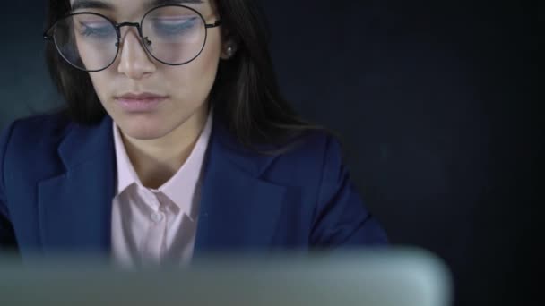 Joven mujer de negocios hermosa sentada en una mesa con un ordenador portátil. Por la noche, una freelancer trabaja remotamente. Cursos de formación en línea, libros de lectura, ver videos en línea . — Vídeos de Stock