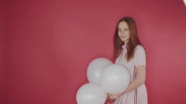 doğum günü, Sevgililer günü konsepti. Mutlu kız kırmızı bir arka plan üzerinde balon bir demet tutan, kız mutlu