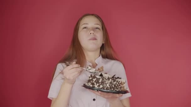 Niedliche Mädchen essen Löffelkuchen, genießen leckeres Gebäck, roter Hintergrund — Stockvideo