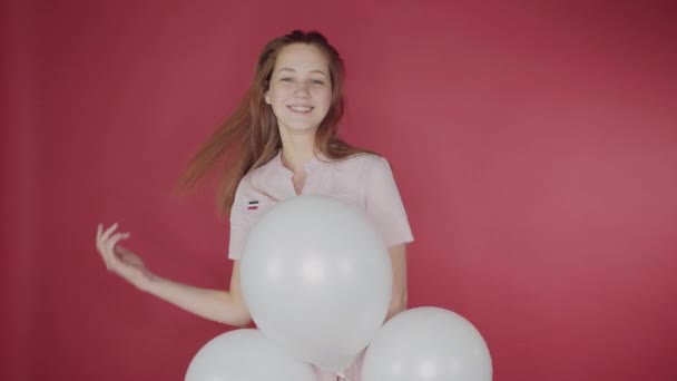 Geburtstag, Valentinstag. glückliches Mädchen hält ein Bündel Luftballons auf rotem Hintergrund, das Mädchen ist glücklich — Stockvideo