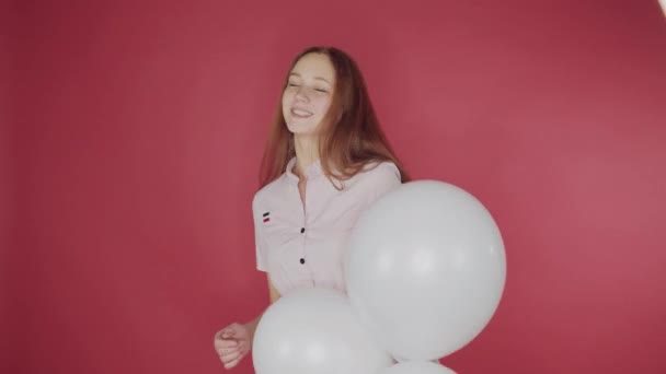 Compleanno, concetto di San Valentino. Ragazza felice che tiene un mucchio di palloncini su uno sfondo rosso, la ragazza è felice — Video Stock