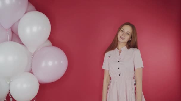 Geburtstag, Valentinstag. glückliches Mädchen hält ein Bündel Luftballons auf rotem Hintergrund, das Mädchen ist glücklich — Stockvideo