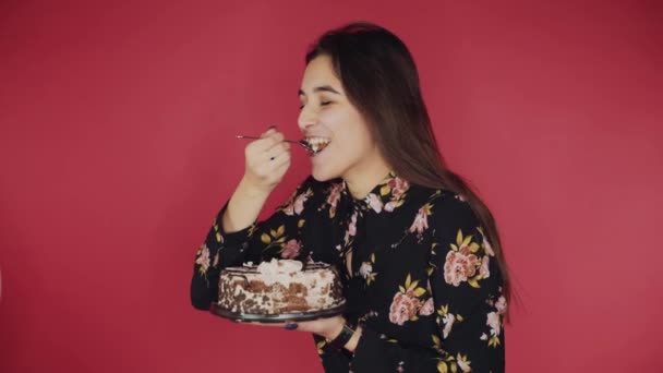 Schattig meisje eten lepel taart, genieten van heerlijke gebakjes, rode achtergrond — Stockvideo