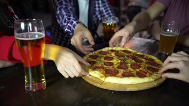 Amigos no bar tiram pedaços de pizza deliciosa da mesa . — Vídeo de Stock