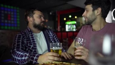 Genç bir adam bir barda bir arkadaşıyla oturur, bira içer, pizza yer. İş gününden sonra iletişim.