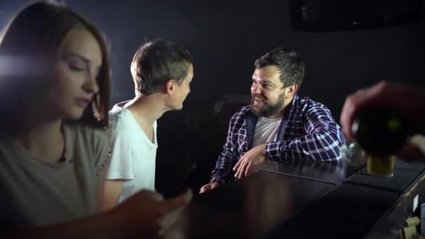 Um pequeno grupo de amigos está sentado em um bar, conversando, bebendo cerveja — Vídeo de Stock