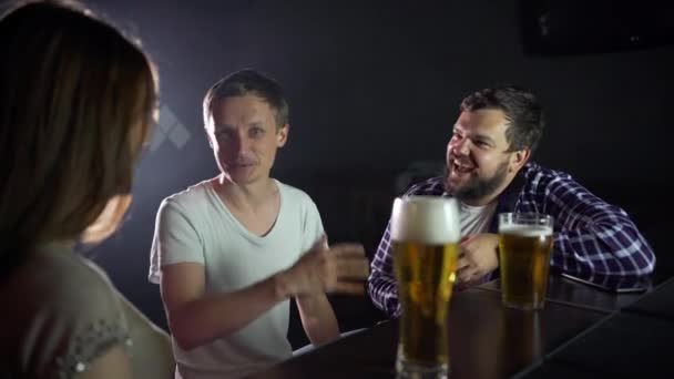 Um pequeno grupo de amigos está sentado em um bar, conversando, bebendo cerveja — Vídeo de Stock