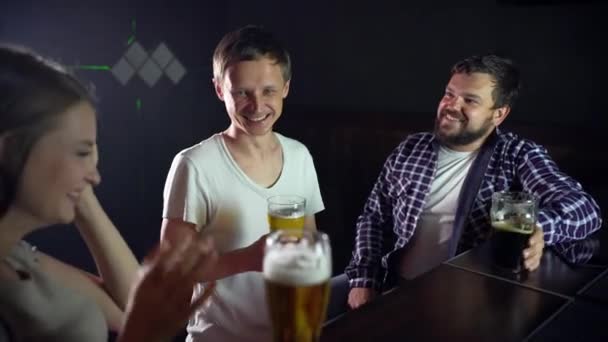 Un pequeño grupo de amigos están sentados en un bar, charlando, bebiendo cerveza — Vídeo de stock