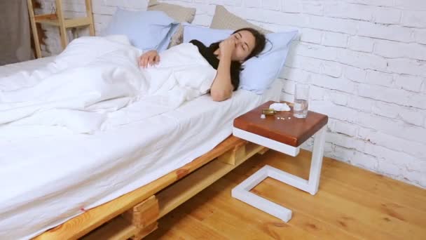 Menina está doente, toma medicação deitada em casa na cama . — Vídeo de Stock
