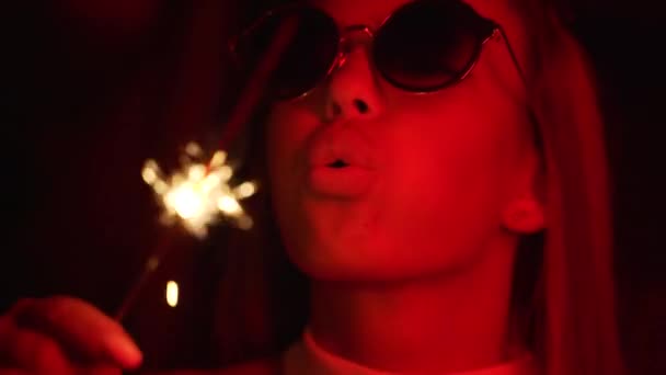 Chica sosteniendo un Sparkler, luz roja de neón. Joven hermosa mujer con gafas sosteniendo un fuego de bengala en llamas . — Vídeos de Stock